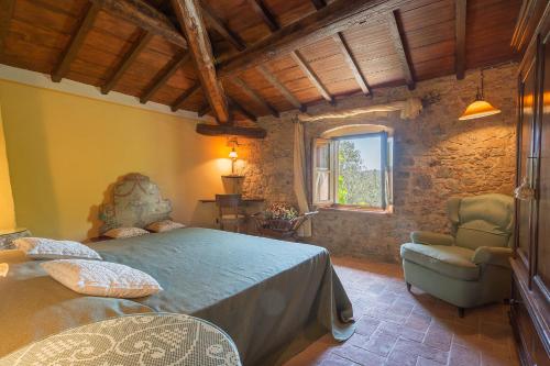 sypialnia z łóżkiem, krzesłem i oknem w obiekcie Relais Colline San Biagio w mieście Carmignano