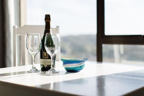 a bottle of wine and two glasses on a table at Garden Route Ilita Lodge in Groot Brak Rivier