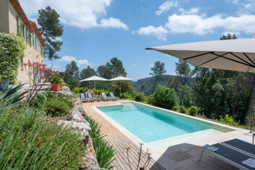 - une piscine dans un jardin avec un parasol dans l'établissement 06TOUR villa Tourrettes, à Tourrettes-sur-Loup