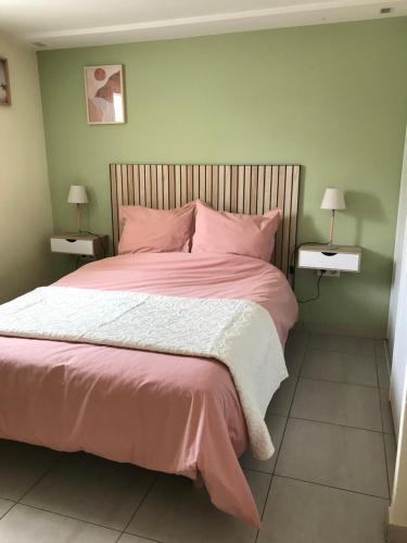 une chambre avec un grand lit avec des draps et des oreillers roses dans l'établissement Appartement deux pièces donnant sur un jardin, à Antibes
