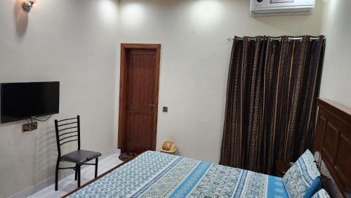 a bedroom with a bed and a tv and a chair at Darul Khair in Lahore