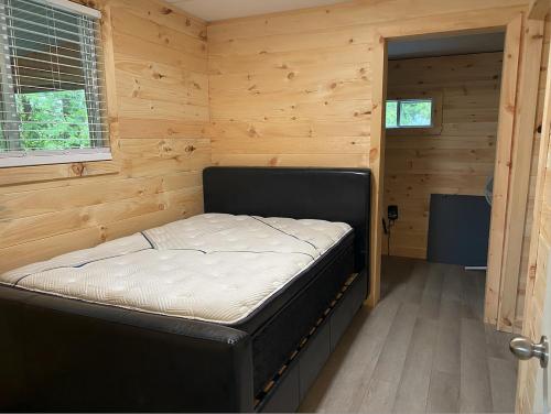 a small bedroom with a bed in a room with wooden walls at Camping Gaulois - Chalet Vert in Scott
