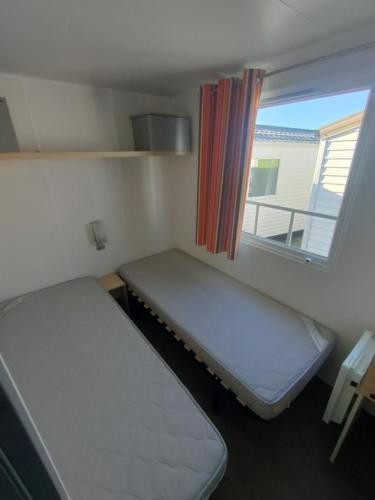une petite chambre avec deux lits et une fenêtre dans l'établissement Village vacances l'endorph'in, à Déols