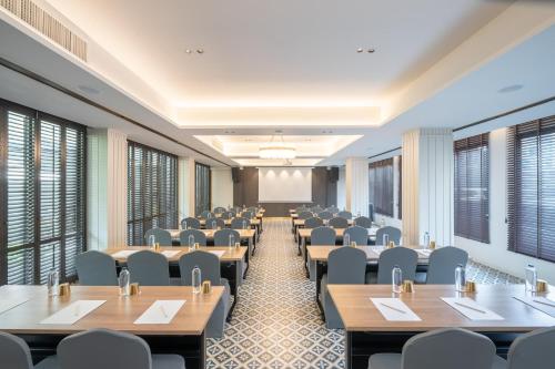 a room with tables and chairs in a room with windows at Pranakorn Heritage Hotel in Bangkok