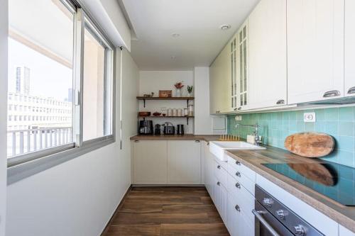 une cuisine avec des placards blancs et une grande fenêtre dans l'établissement Spacious & Cozy 2-Room with Balcony, à Puteaux