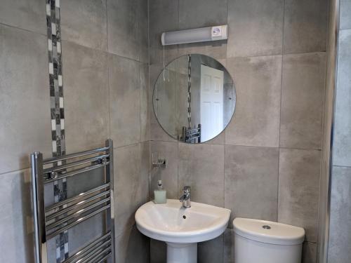 een badkamer met een wastafel, een spiegel en een toilet bij The Priory in Shanklin