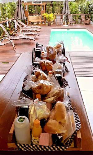 een dienblad met eten op een tafel naast een zwembad bij Pousada Rosa Maria in Praia do Rosa