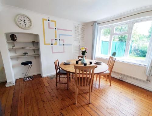 a dining room with a table and chairs and a clock at Epicsa - Corporate & Family Stay in 3 Bedroom House with Garden, FREE parking in Cambridge
