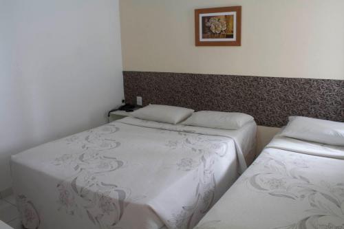 two twin beds in a room with a picture on the wall at Hotel Agua Marinha in Natal