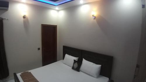 a bedroom with a bed with white sheets and pillows at Darul Khair in Lahore