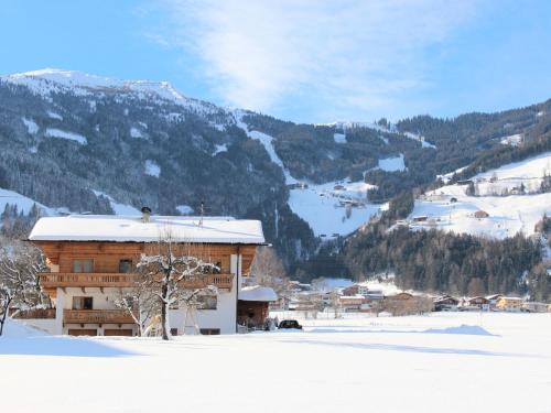 a building in the snow with a mountain in the background at Apartment Gasteighof-6 by Interhome in Fügen