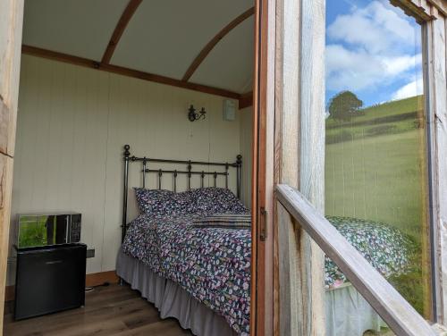 een bed in een kleine kamer met een raam bij Top of the Rock Glamping in Trefeglwys