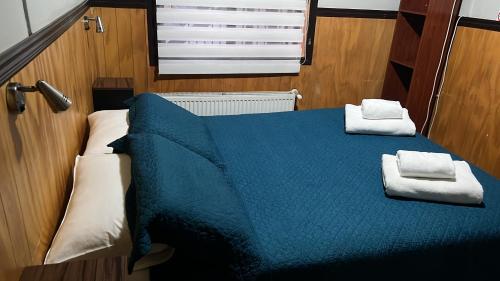 a bedroom with a blue bed with towels on it at HOSTAL VICTORIA in Punta Arenas