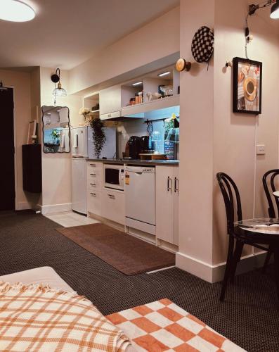 a kitchen with white cabinets and a table and a bed at Cosy duplex 2bed1bath apartment by Melbourne Emporium in Melbourne