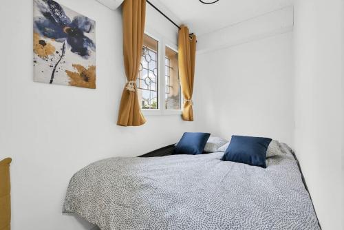 une chambre avec un lit avec des oreillers bleus et une fenêtre dans l'établissement La lumière du Midi-Oncopole à 5 minutes-clim, à Toulouse
