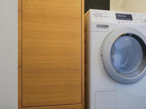 a washing machine is next to a wooden cabinet at Apartment Rosablanche E003A by Interhome in Siviez