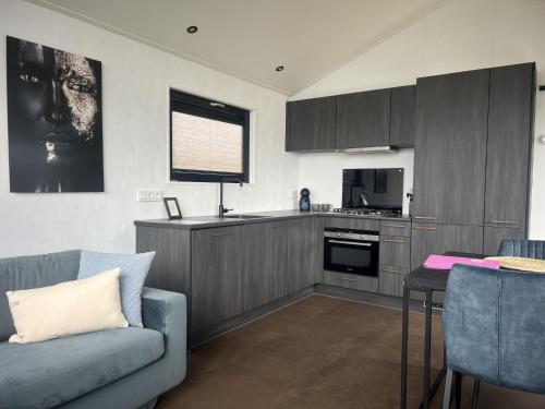 a living room with a couch and a kitchen at Holiday Home De Zeeparel by Interhome in Scherpenisse