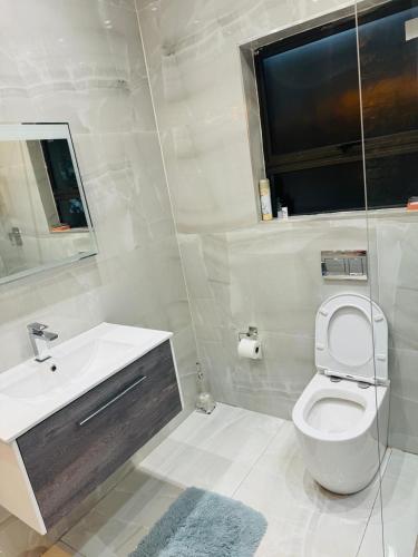 a white bathroom with a toilet and a sink at Icebolethu Guest House in Standerton