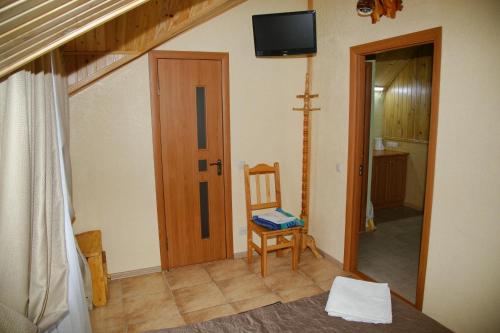 a room with a chair and a television on the wall at Mini-hotel Yandrusi in Kamianets-Podilskyi
