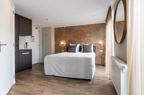 een slaapkamer met een groot wit bed en een spiegel bij Juuls Domburg in Domburg