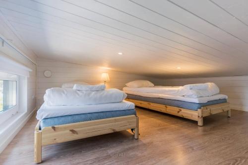 twee bedden in een kamer met houten vloeren bij Merikruunu tähdistöhuvila Otava 15 in Dragsfjärd