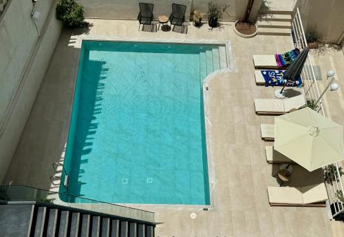 uma vista sobre uma piscina com cadeiras e um guarda-sol em Floral Hotel em Hersonissos