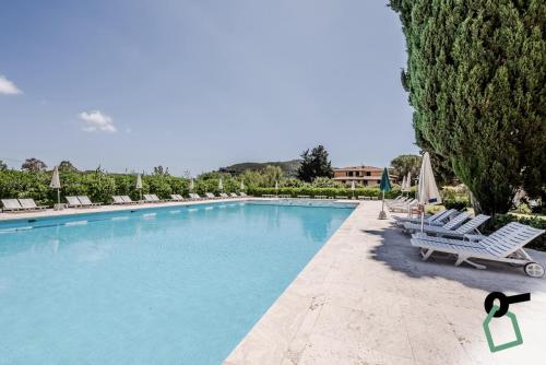 a large swimming pool with lounge chairs and trees at HOTIDAY Hotel Isola D'Elba in Lacona