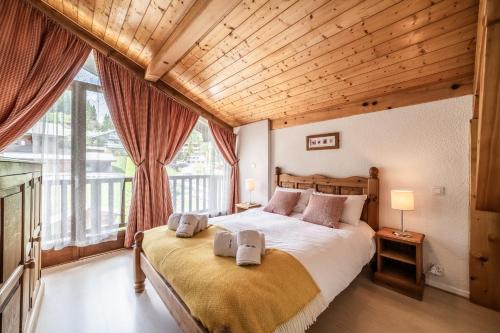une chambre avec un grand lit avec un plafond en bois dans l'établissement Chalet Beauséjour, à Morzine
