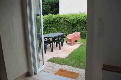 a patio with a table and chairs and a pink chair at Le Cocon des Mardors in Couternon