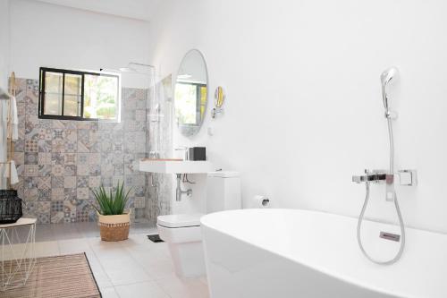 a white bathroom with a tub and a toilet at Le Palais d'Akwa in Abidjan