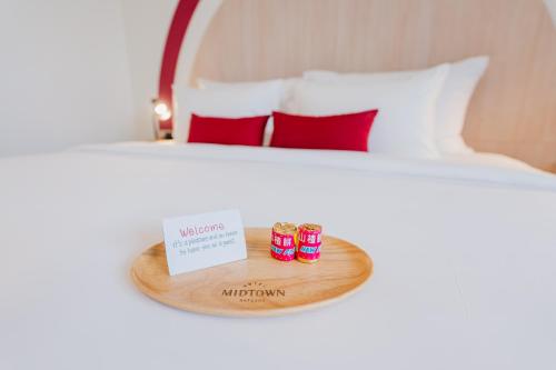 a bed with red pillows and a tray with threeousand at Hotel Midtown Ratsada in Phuket Town