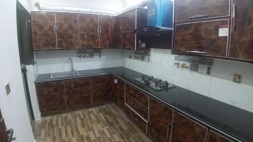 an empty kitchen with wooden cabinets and a sink at Darul Khair in Lahore
