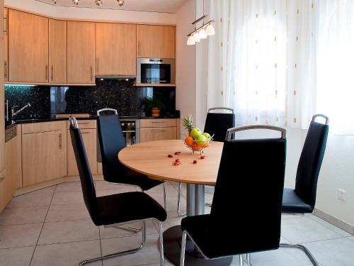 cocina con mesa de madera y sillas negras en Apartment Iris A-3 by Interhome, en Leukerbad