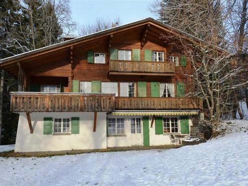 een groot houten huis met een terras in de sneeuw bij Apartment Les Erables- Chalet by Interhome in Gstaad