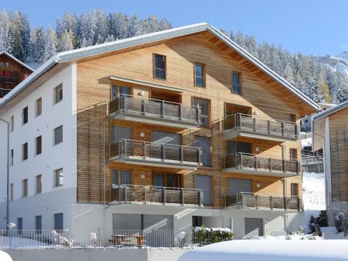 ein großes Holzgebäude mit Balkon im Schnee in der Unterkunft Apartment Raber by Interhome in Churwalden