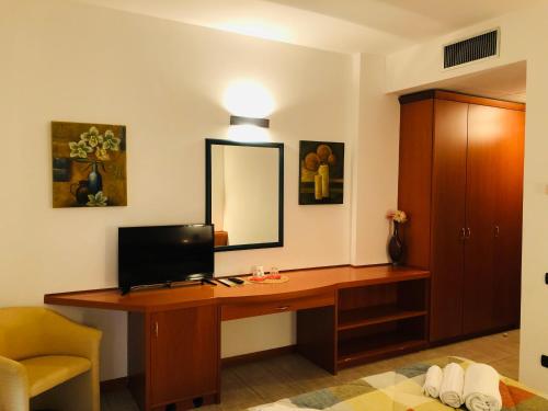 een kamer met een bureau, een televisie en een spiegel bij Hotel Softwood in Recanati