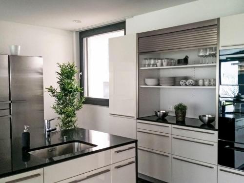 a kitchen with white cabinets and a stainless steel refrigerator at Holiday Home Villa am See 3 by Interhome in Sisikon