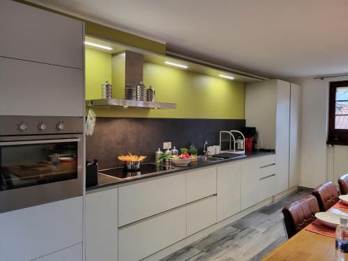a kitchen with white cabinets and yellow walls at Holiday Home Dumont by Interhome in Manno