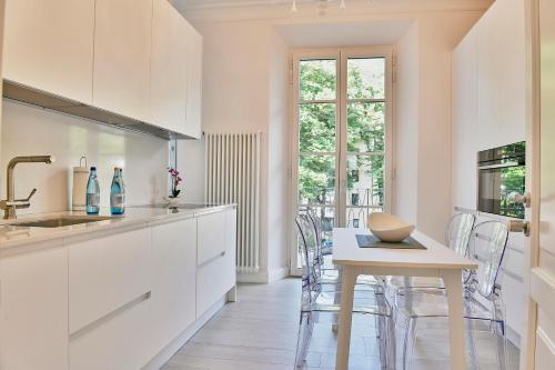 a kitchen with white cabinets and a table with chairs at Wosching Haus Roemer Living in Merano