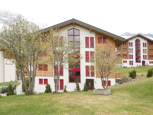 a large white building with red windows and trees at Apartment Snow-Fun B by Interhome in Saas-Fee