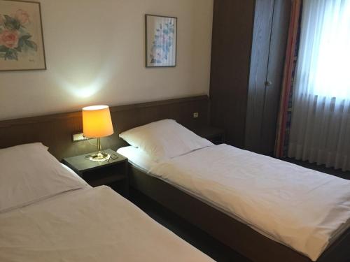 two beds in a hotel room with a lamp on a table at Hotel Görres in Wachtberg