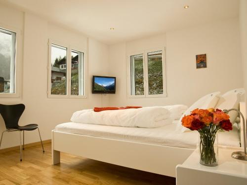 a white bedroom with a bed and a vase of flowers at Apartment B41 by Interhome in Leukerbad
