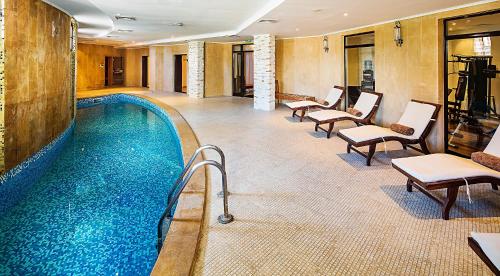 a pool in a hotel room with chairs and tables at The Cliff Hotel and Holiday Apartments by Flat Mаnаger in Obzor