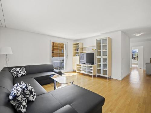 ein Wohnzimmer mit einem schwarzen Sofa und einem TV in der Unterkunft Apartment Moser by Interhome in Churwalden