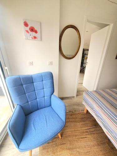 une chaise bleue dans une pièce avec un miroir dans l'établissement L'idylle du Vercors, à Chatuzange-le-Goubet
