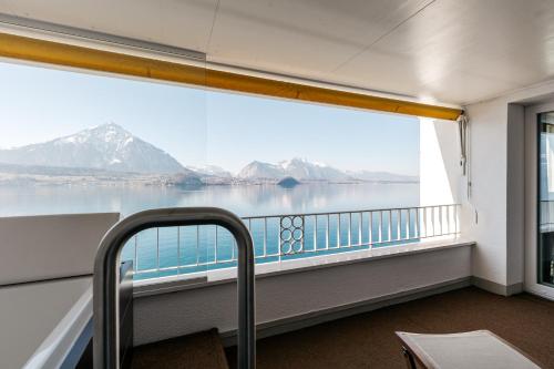 um quarto com uma janela com vista para a água e para as montanhas em BEATUS Wellness- & Spa-Hotel em Merligen