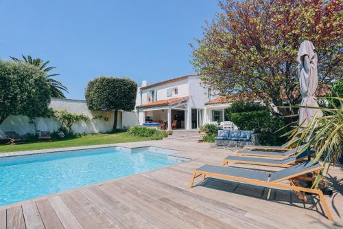 une piscine avec des chaises longues à côté d'une maison dans l'établissement Villa des Terroirs, à La Couarde-sur-Mer