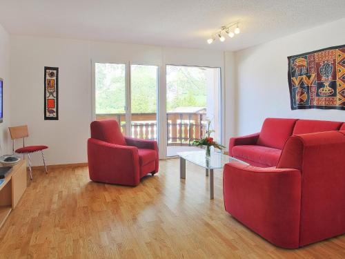 una sala de estar con 2 sillas rojas y una mesa. en Apartment Iris A-1 by Interhome en Leukerbad
