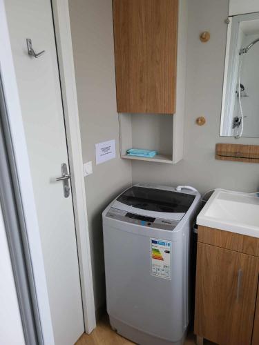 une petite cuisine avec une machine à laver et un évier dans l'établissement Mobilhome au bord de l'eau, à Lège-Cap-Ferret