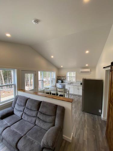 a living room with a couch and a kitchen at The Hideaway Cottage with Private trails in Waweig